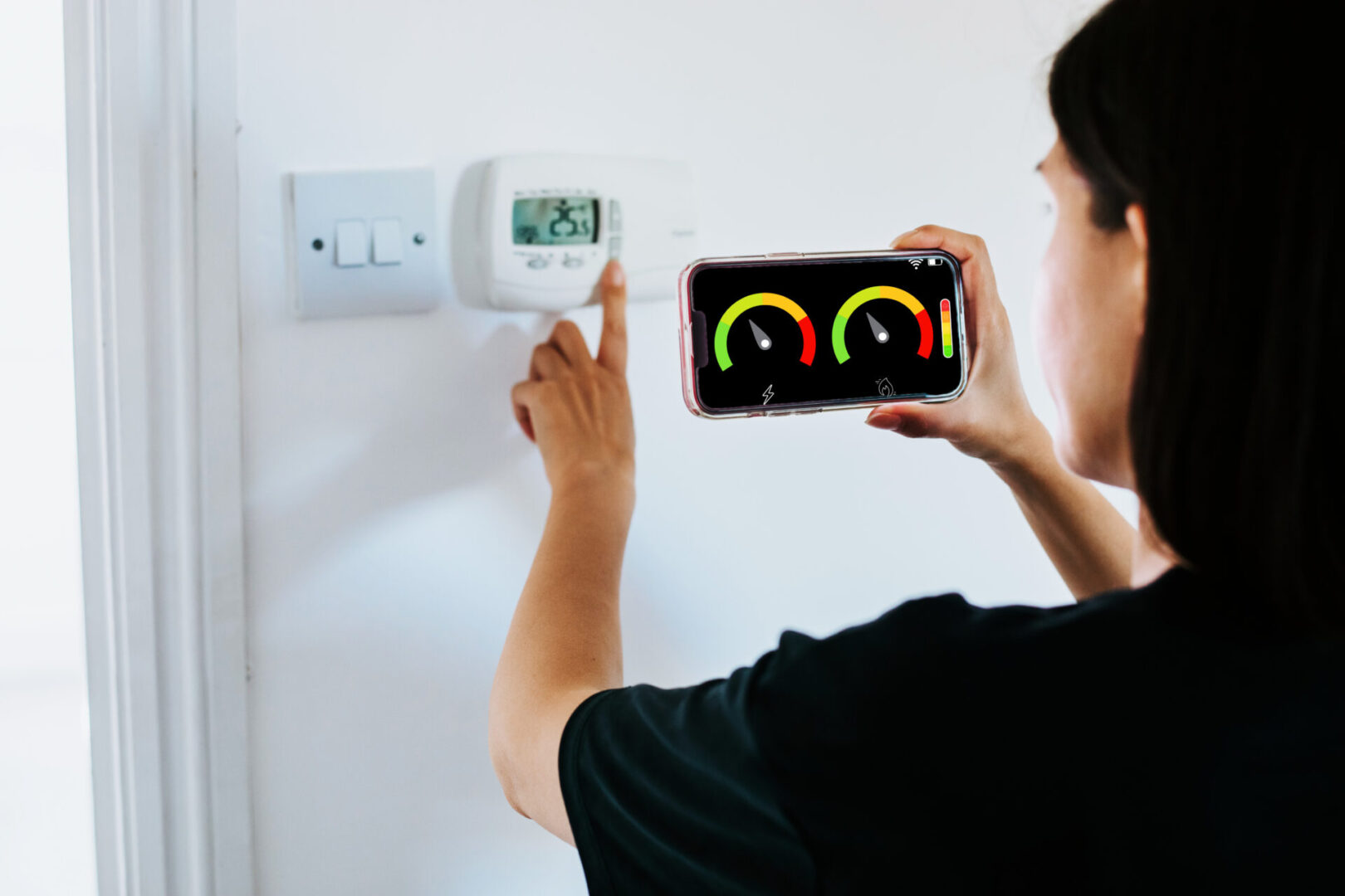 Person adjusting thermostat with smartphone app.