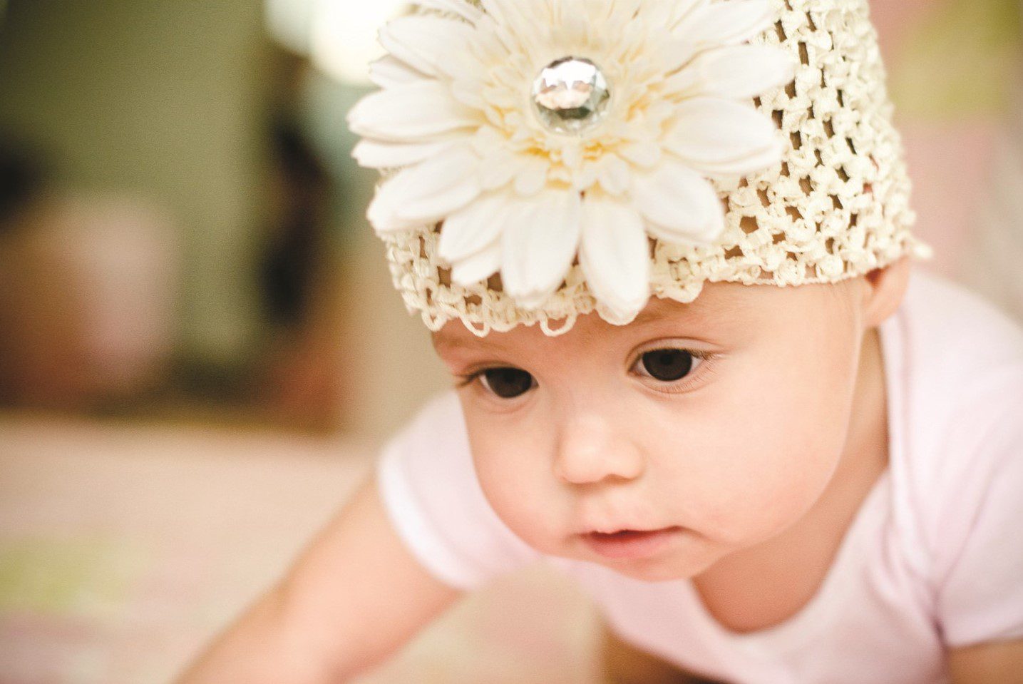Baby wearing a floral hat, crawling.