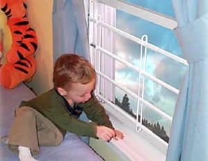 Child playing near a window with bars.