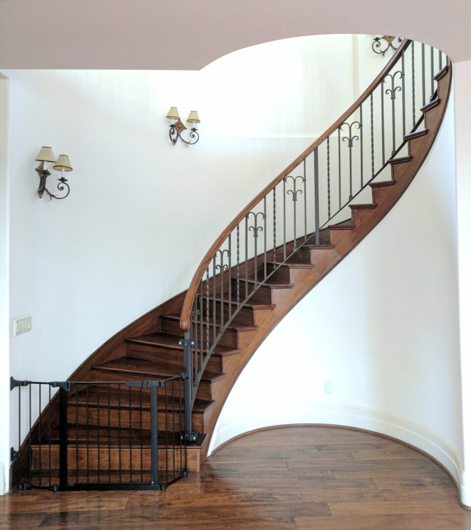 Curved wooden staircase with black metal railing.