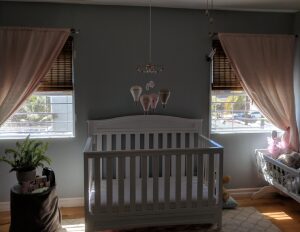 Nursery with crib and pink curtains.